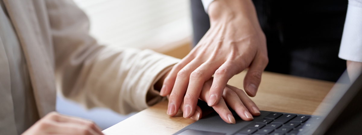 Männliche Hand legt sich auf weibliche Hand über eine Tastatur