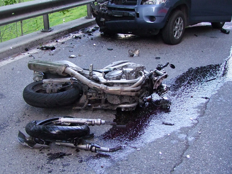 Das total beschädigte Motorrad. Im Hintergrund der Personenwagen.