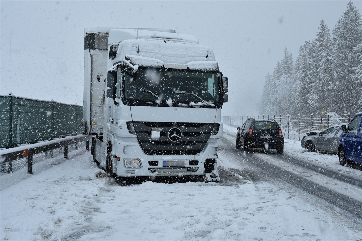 Die total verschneite A13. Links von vorne das an der Front beschädigte Sattelmotofahrzeug, rechts am Strassenrand das total beschädigte Auto.