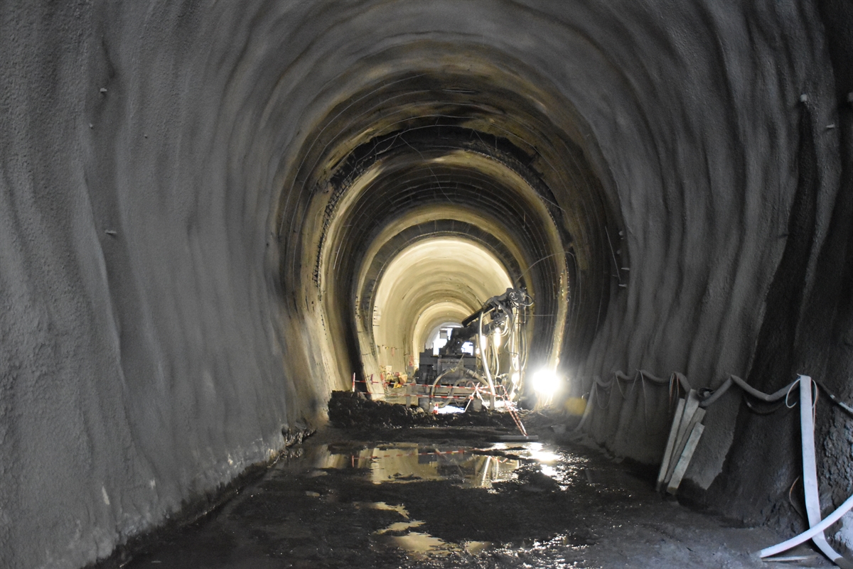 Der Bahntunnel von innen mit einer Maschine zum Auftragen des Spritzbetons. Am Boden der von der Decke gelöste Spritzbeton.