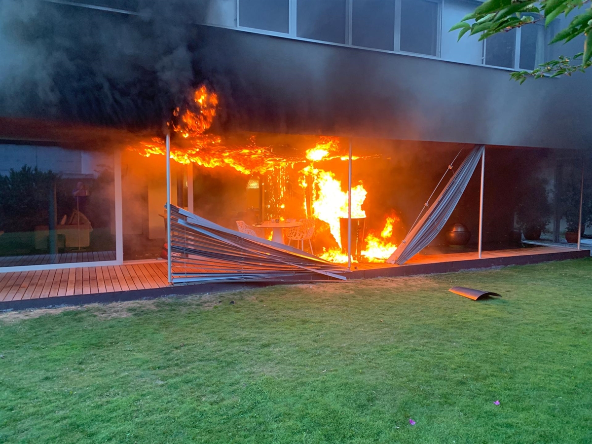 Brennender Gasgrill. Flammen gehen auf das Gebäude über.