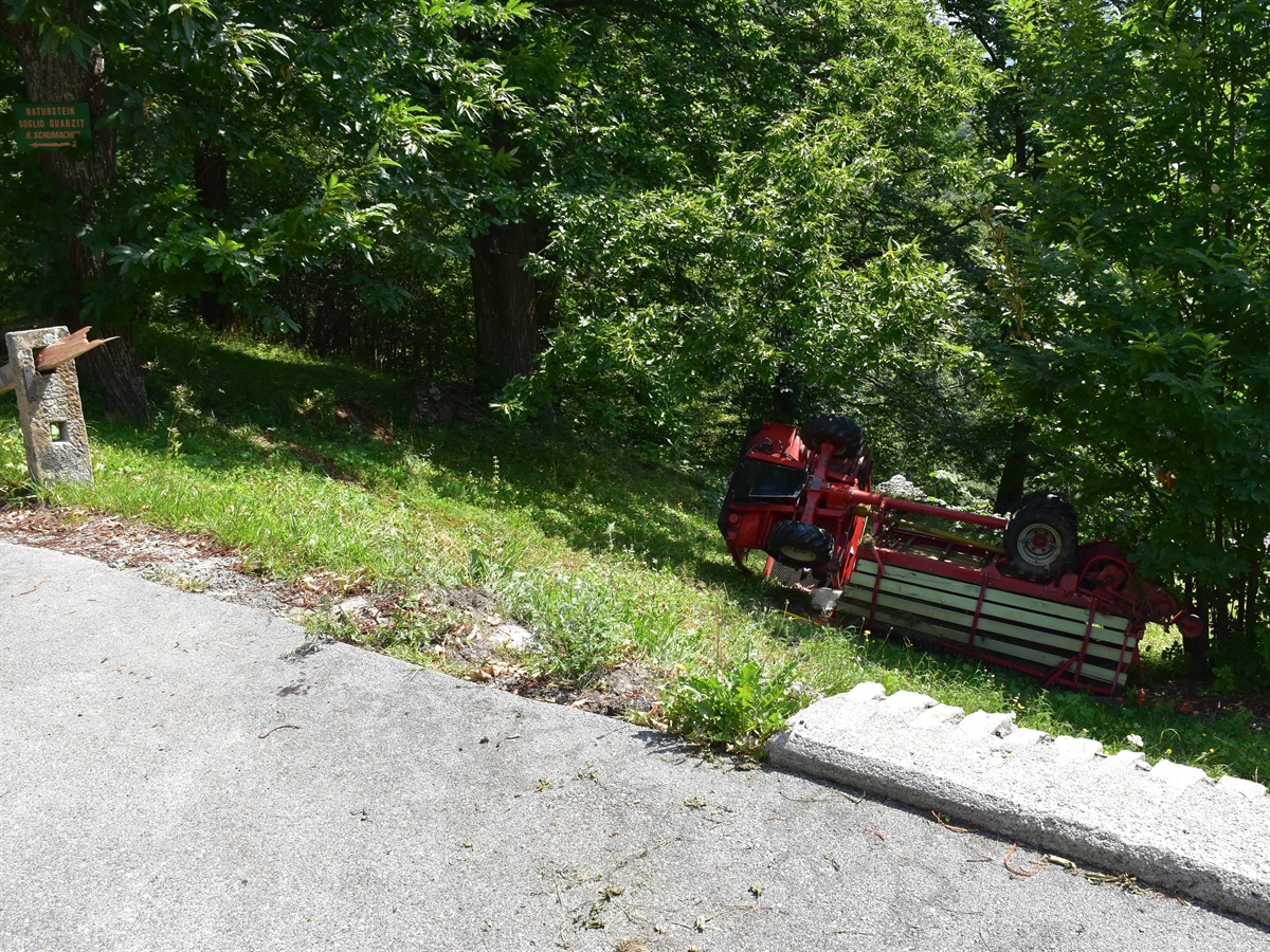 Motorkarren seitlich an einem Baum liegend neben der Strasse am Ende einer Böschung.