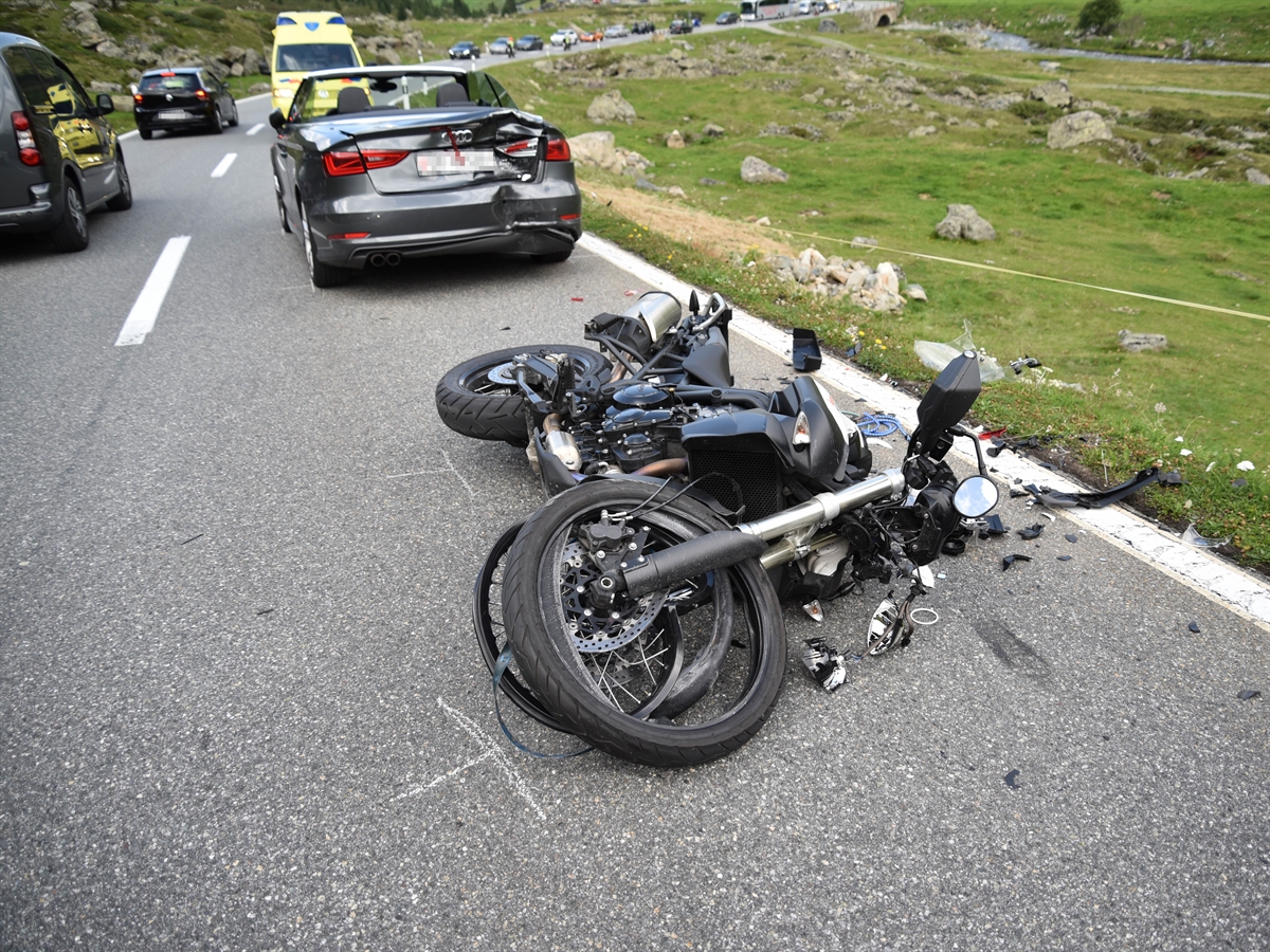Unfallstelle oberhalb Tschuggen in Davos. Auto mit Schaden am Fahrzeugheck im Hintergrund. Auf der Strasse liegendes total beschädigtes Motorrad.
