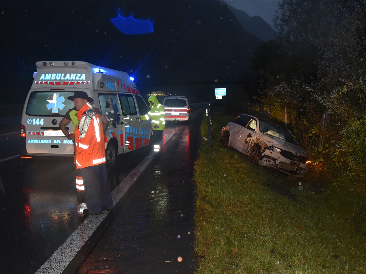 Total beschädigtes Auto im Grünstreifen zwischen Wildschutzzaun und Fahrbahn. Einsatzkräfte der Polizei und der Ambulanz mit den jeweiligen Fahrzeugen.