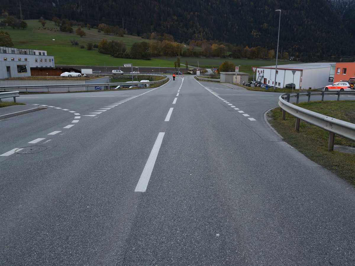 Unfallörtlichkeit aus Sicht des Motorradfahrers mit der Verzweigung in Richtung Italienische Strasse gesehen. Von links einmündend die Zufahrt zur Burgstrasse aus der Gewerbezone Paleu Sura.