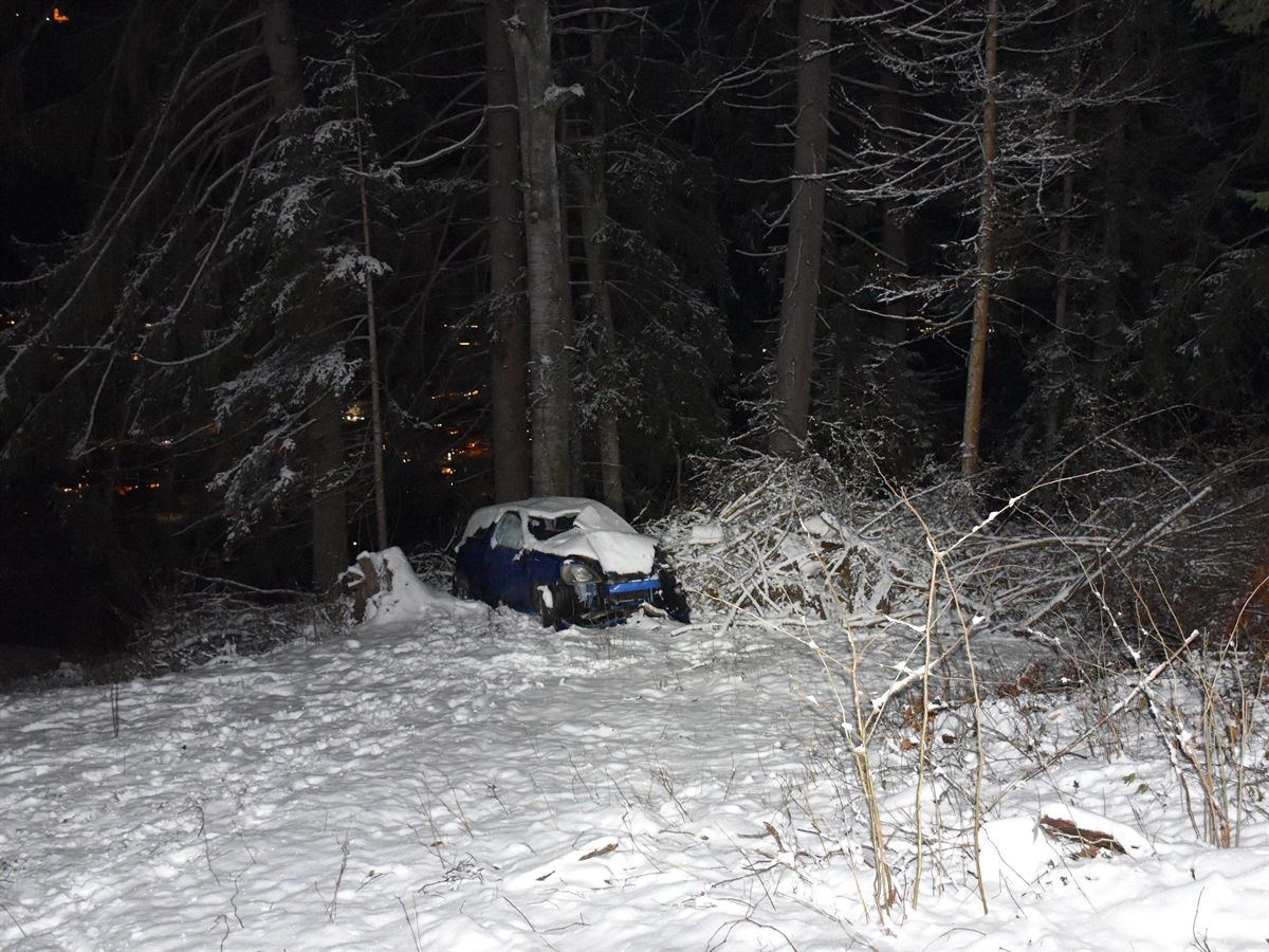 Unfallauto zwischen den Bäumen. Total beschädigt und mit Schnee bedeckt.