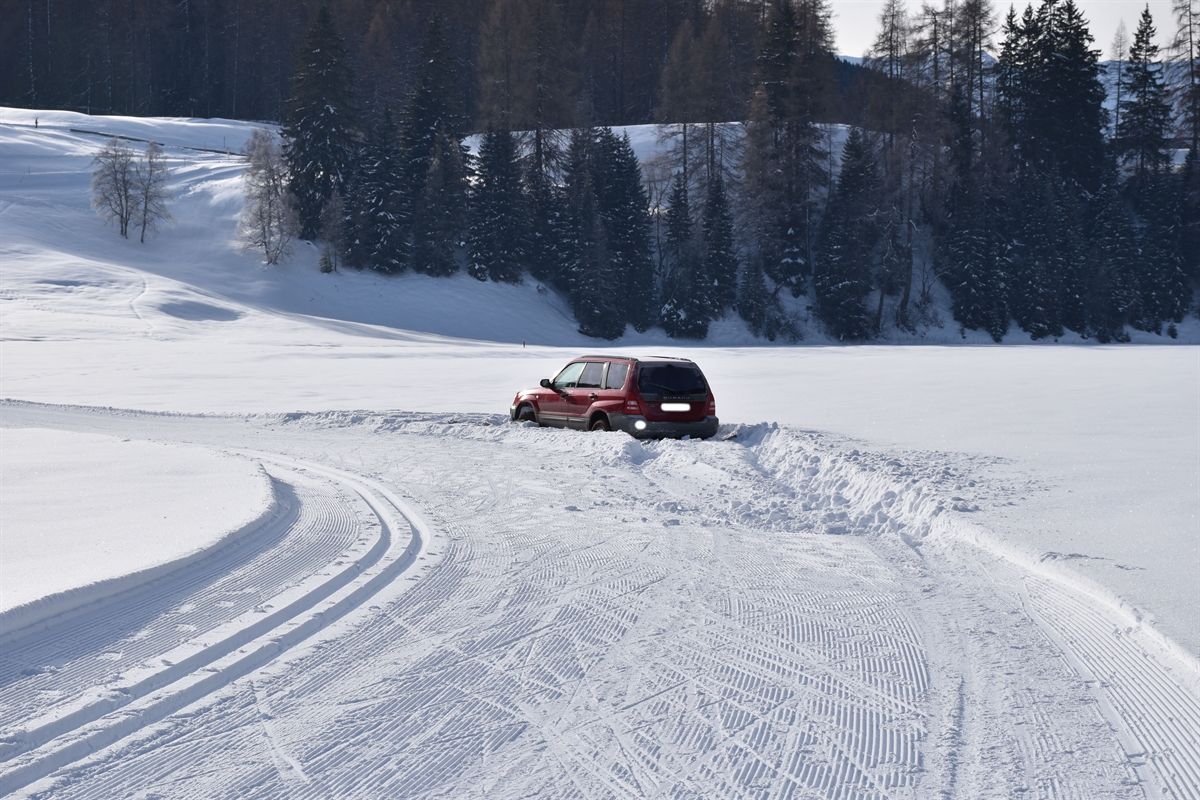 Langlaufloipe mit Linkskurve. Auto befindet sich rechts im tiefen Schnee.
