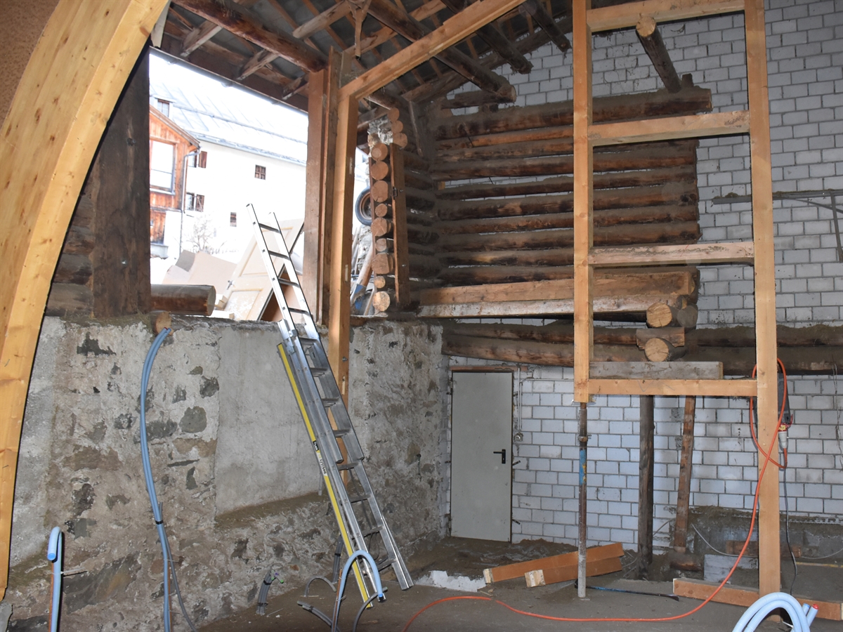 Baustelle im Innern des Stalls. Holzkonstruktion im Hintergrund mit Treppenabgang ins Untergeschoss