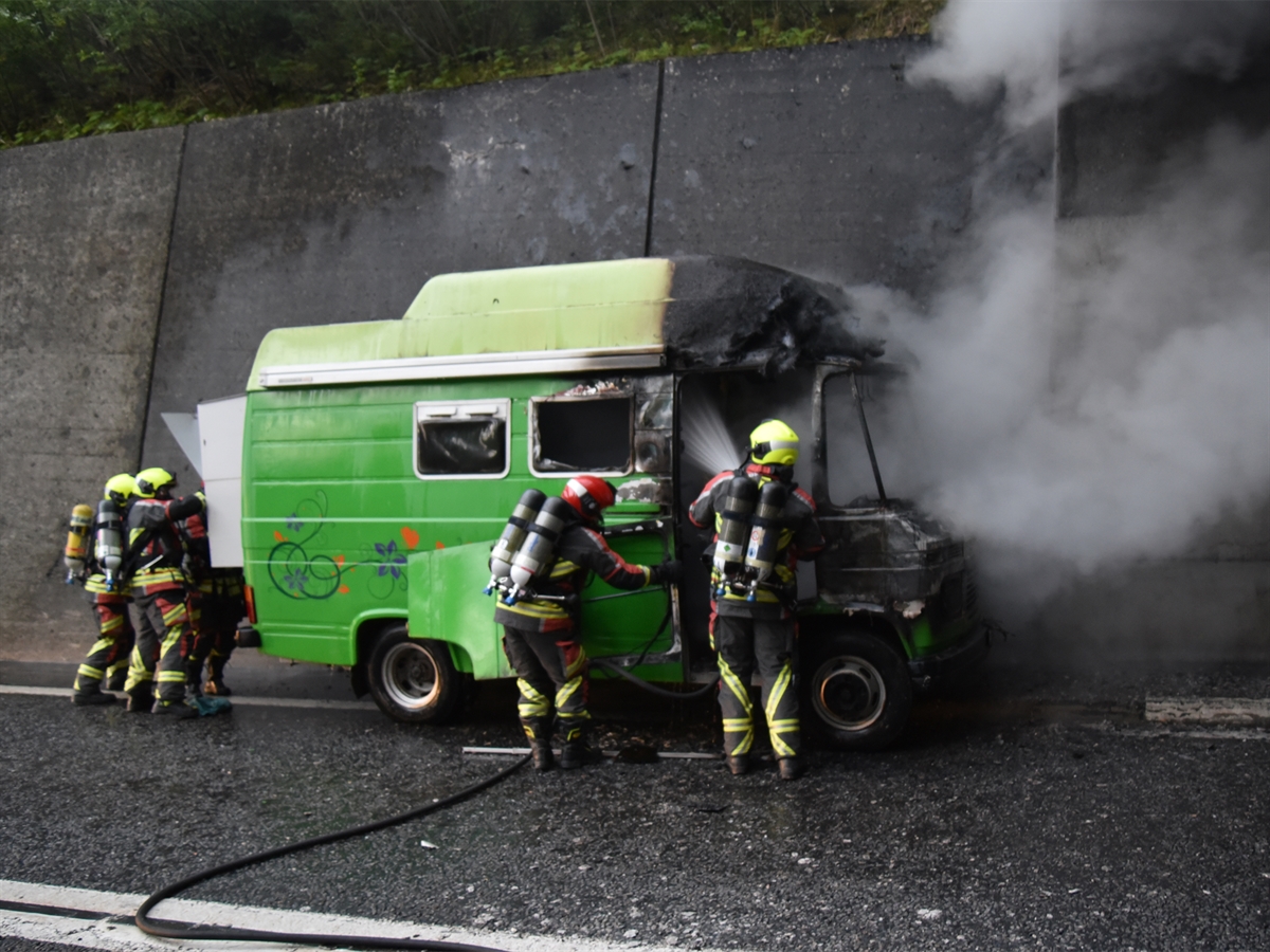 Die Einsatzkräfte der Strassenrettung Feuerwehr Andeer bei den Löscharbeiten des grünen, in die Jahre gekommenen Wohnmobils.