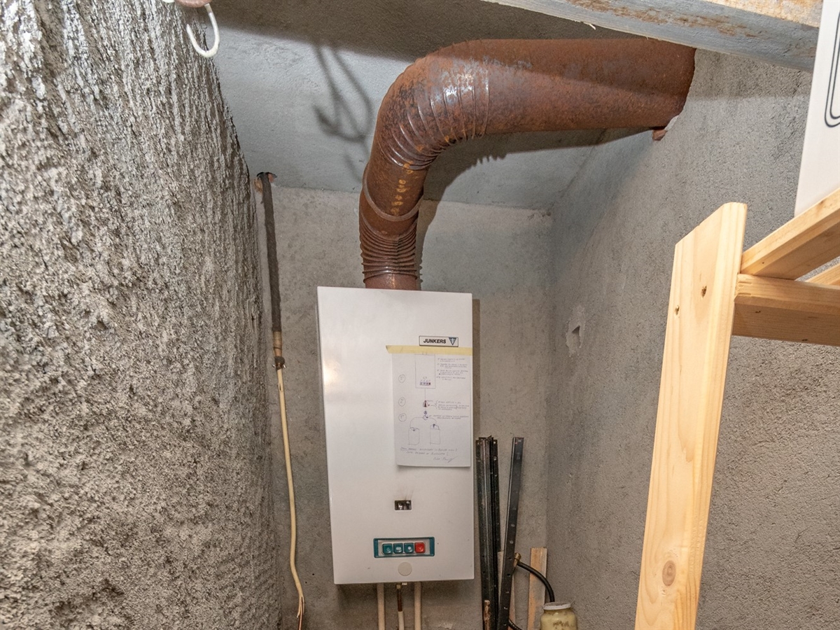 Durchlauferhitzer an der Wand mit dem Abgasrohr an der Decke des Raums