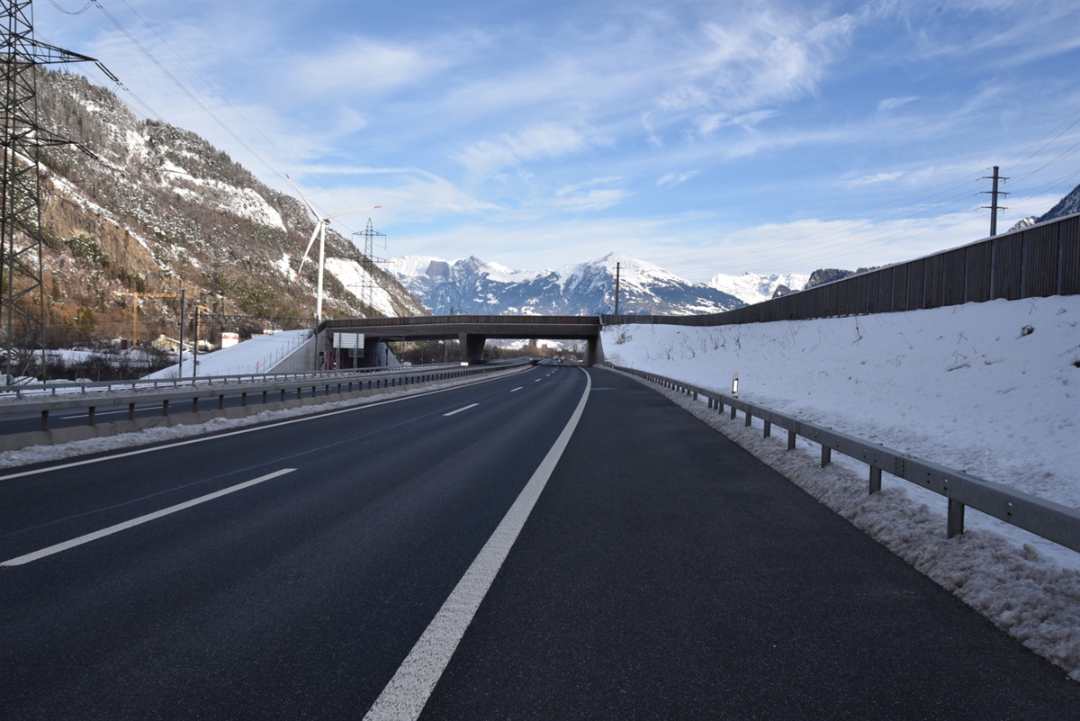 Die Nordspur der Autobahn A13 nach dem Anschluss Chur Nord. Über die Fahrspuren führt die Wildüberführungsbrücke. Links neben der A13 steht das Windrad.