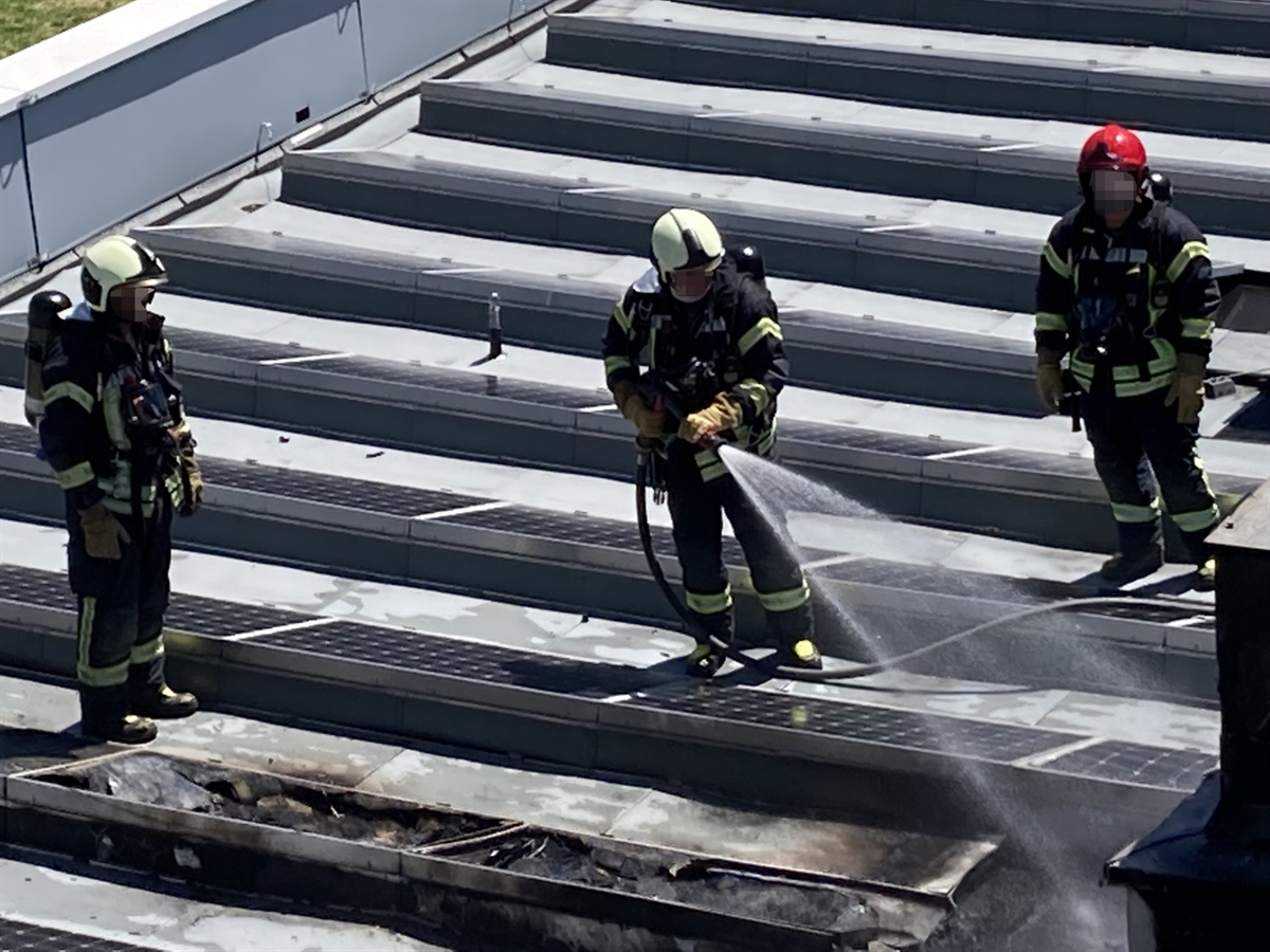 Feuerwehrleute auf dem Flachdach am Feuer löschen