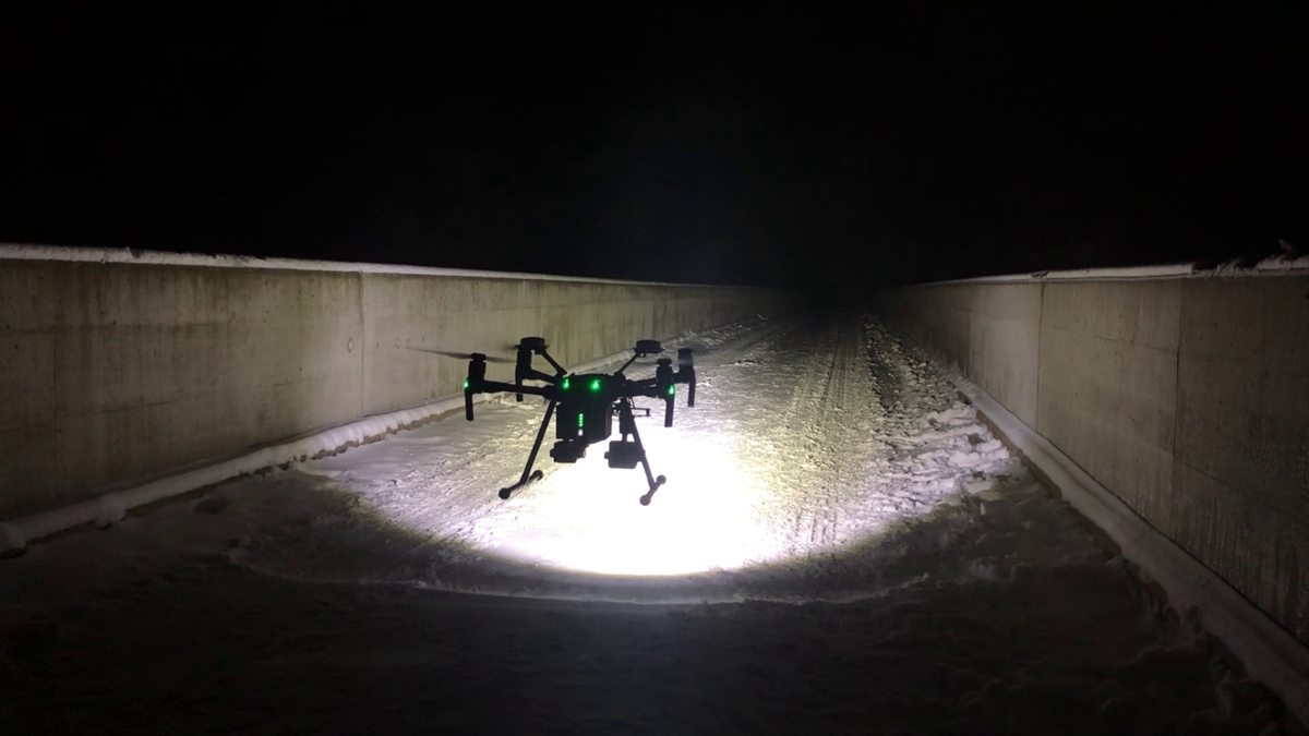 Fliegende Drohne mit Scheinwerfer auf der Salginatobelbrücke.