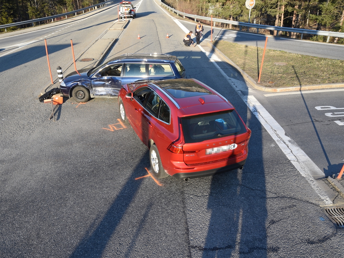 Auf der Querverbindung stehen die beiden Unfallfahrzeuge. Ein blaues Fahrzeug steht quer vor einem roten Auto. Im Hintergrund steht ein Patrouillenfahrzeug. Eine Polizistin sowie ein Polizist sichern Spuren auf der Fahrbahn.