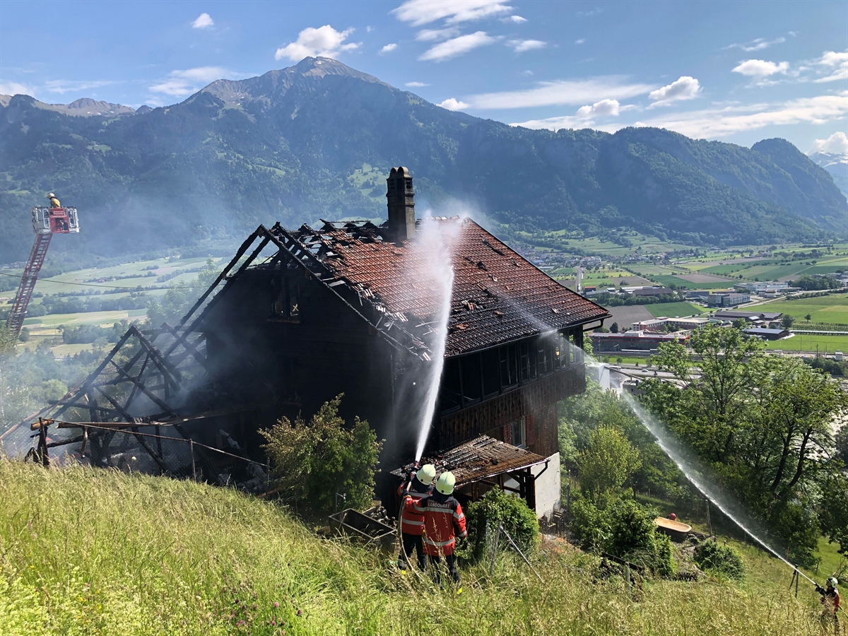 Feuerwehrleute löschen das brennende Holzhaus mit Stall