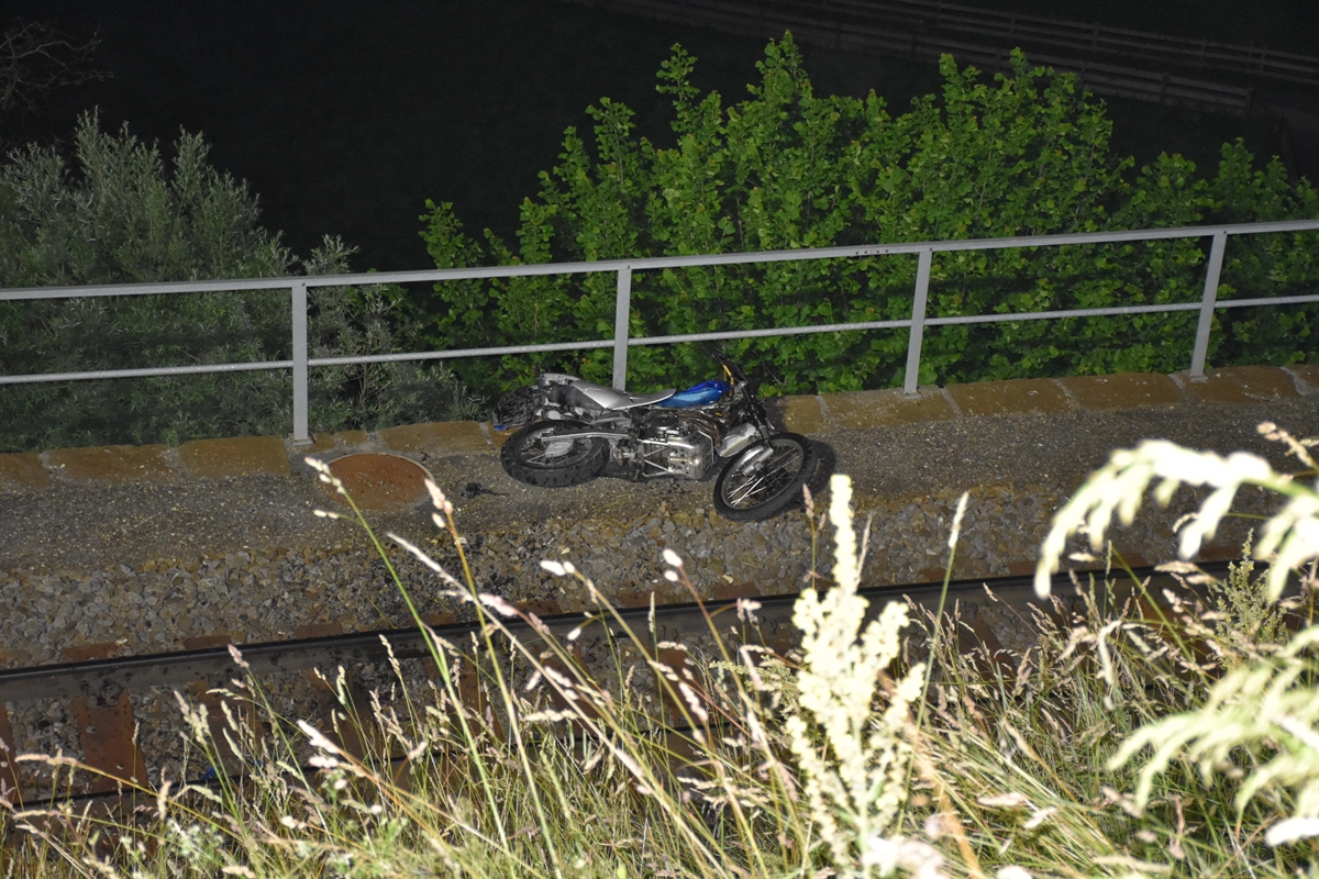 Blick von oben auf die Gleise der Rhätischen Bahn. Das beschädigte Motorrad liegt neben den Gleisen.