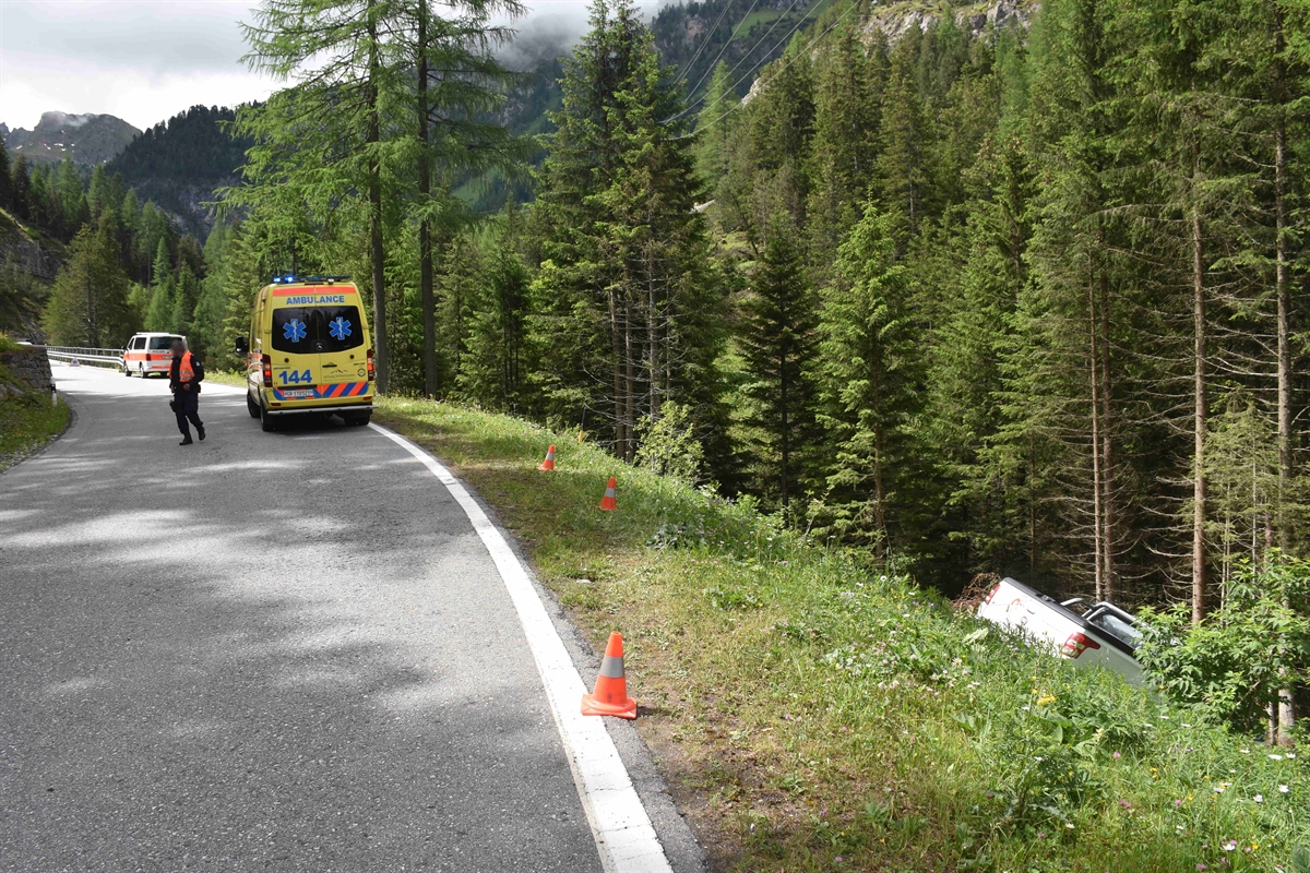 Lieferwagen im steilen Abhang, Ambulanz und Polizei auf der Strasse vor Ort.