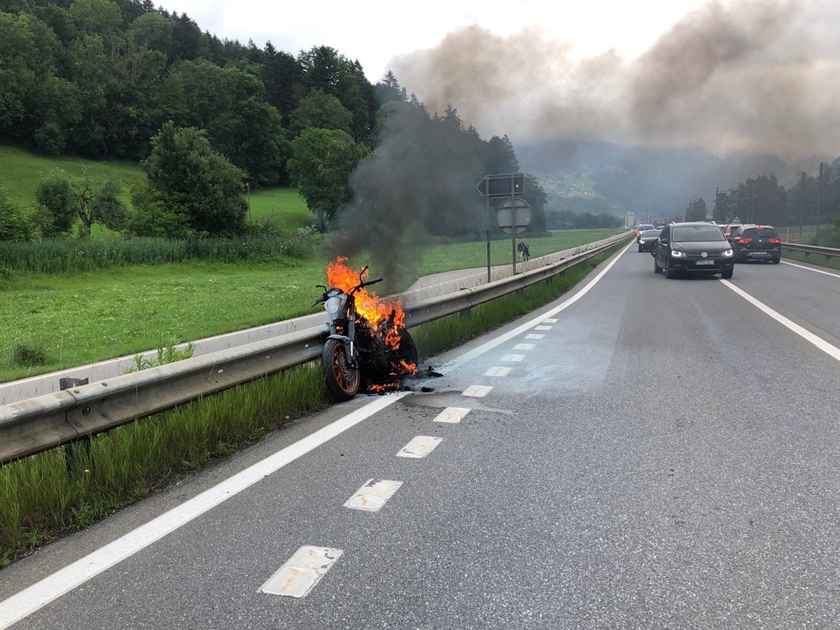 Links an der Leitplanke angelehnt von vorne das brennende Motorrad. Rechts davon die N28 und Autos.