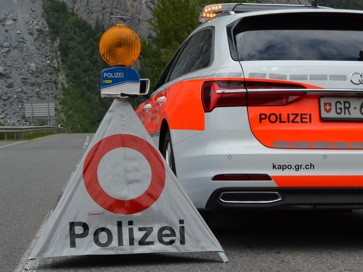 Patrouillenfahrzeug der Kantonspolizei Graubünden. Rechts daneben steht ein Faltsignal mit einem allgemeinen Fahrverbot. Auf dem Signal steckt ein Warnblinklicht.