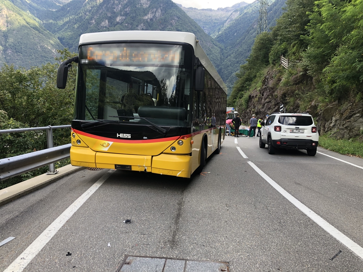 Beschädigtes Postauto im Vordergrund. Im Hintergrund wird der verletzte Motorradfahrer betreut