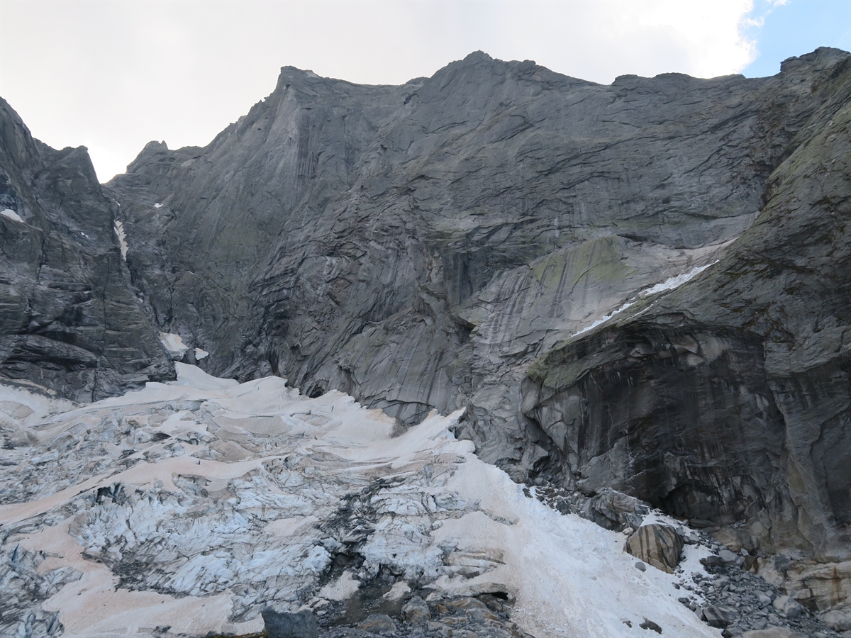 Unten der Gletscher und dahinter oben die Nordwand des Piz Badile. Der Badile grenzt sich an den Horizont ab.