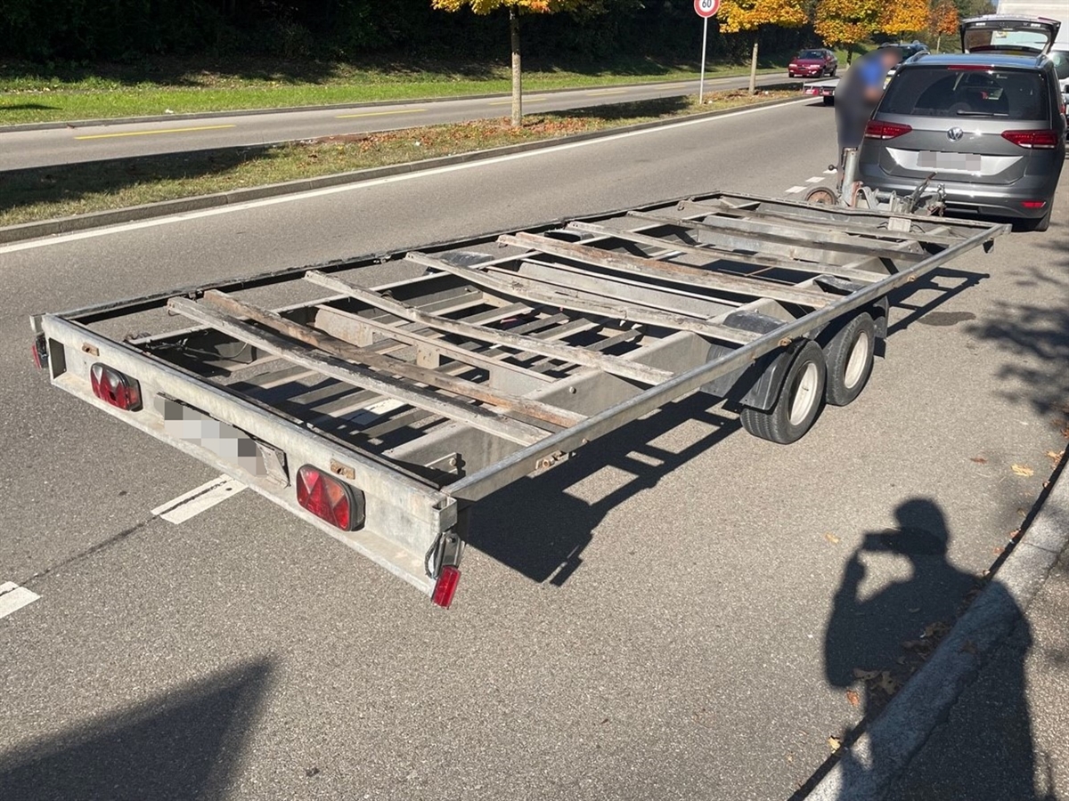 Der durch die Kapo ZH angehaltene Personenwagen mit dem Anhänger. Ein Polizist steht beim Personenwagen.