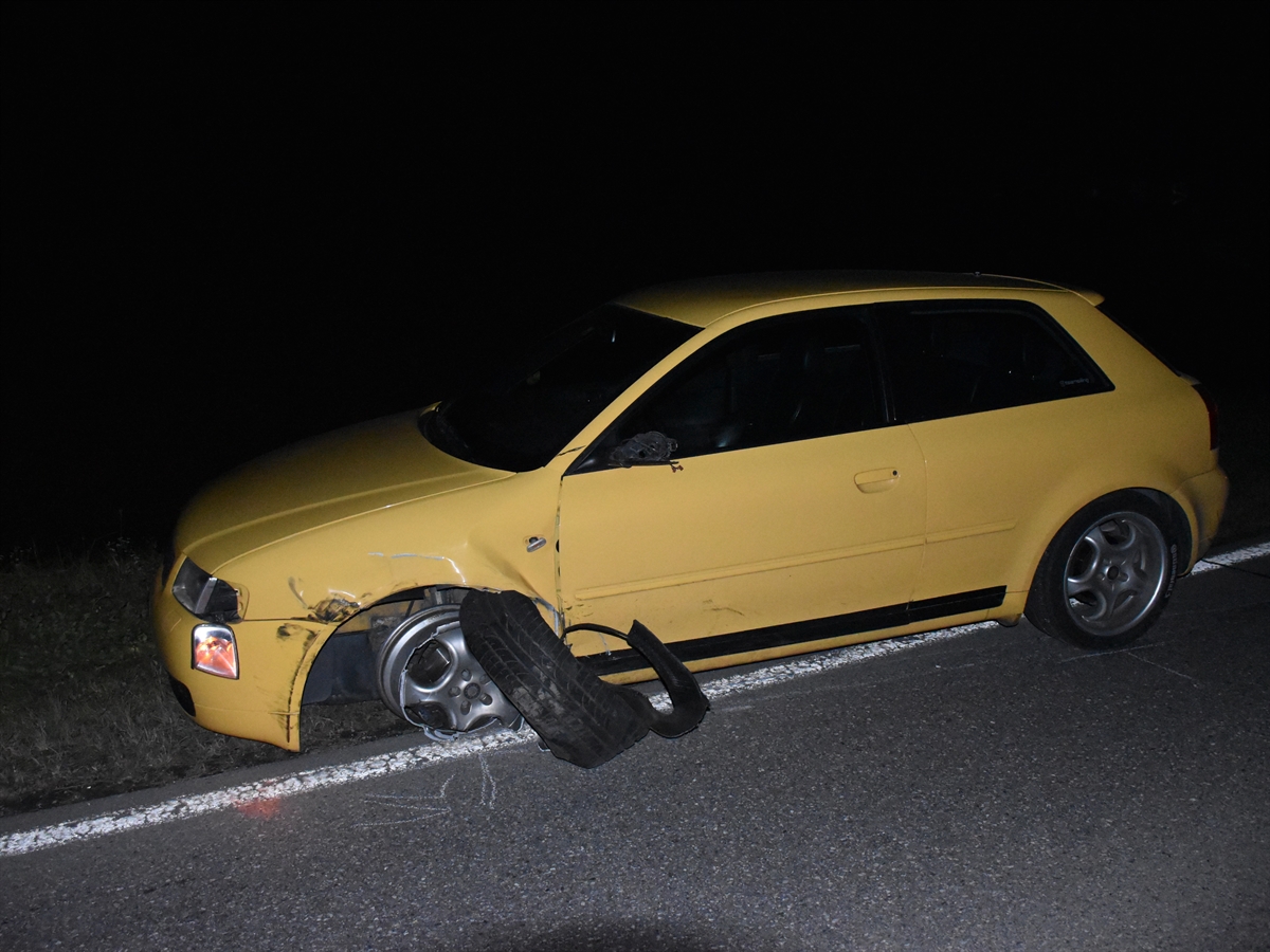 Die beschädigte linke Fahrzeugseite eines gelben Autos. Der Reifen des Vorderrades, dieses ist nach hinten verschoben, ist nicht mehr auf der Felge.