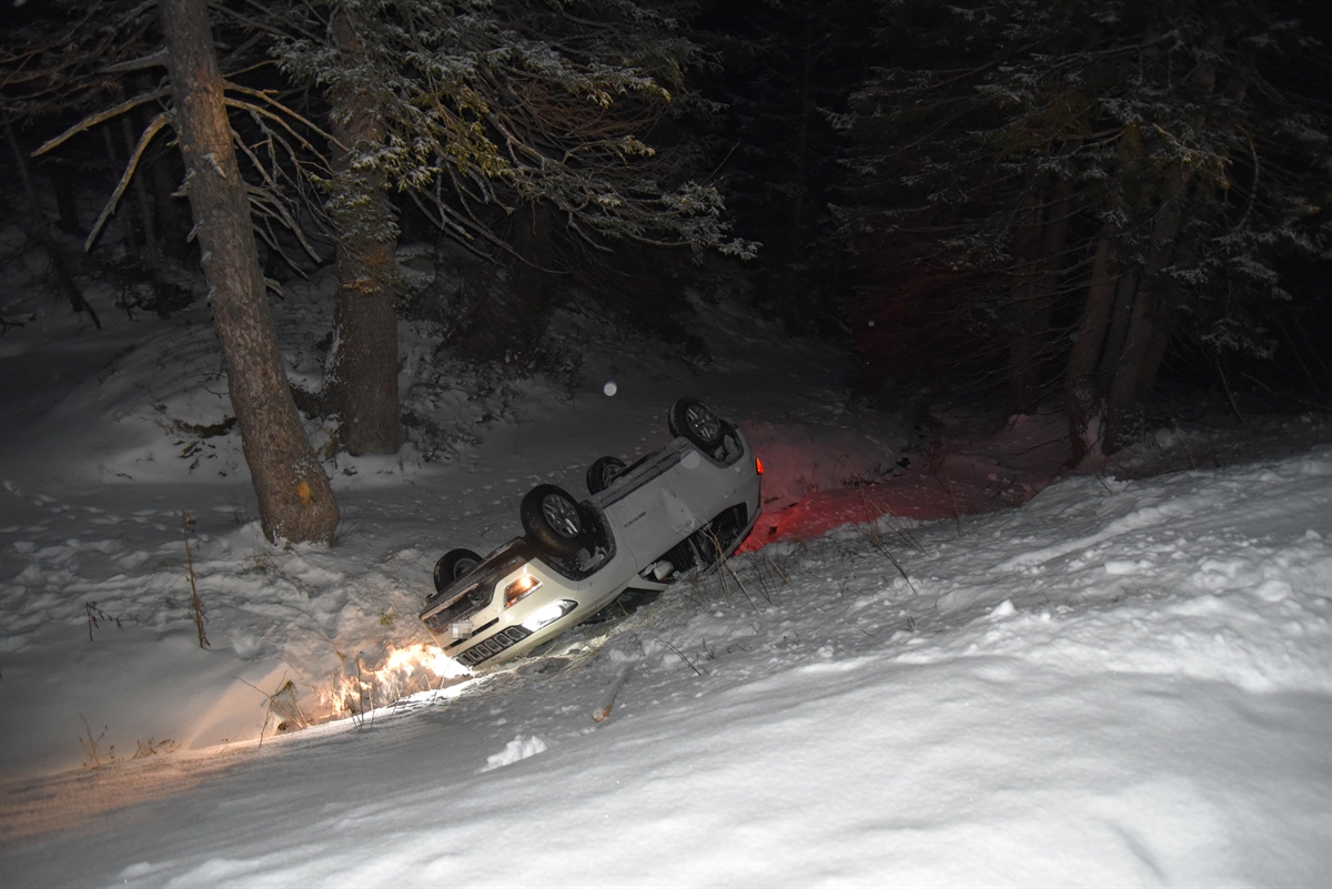 Weisses Unfallauto im schneebedeckten Abhang im Wald