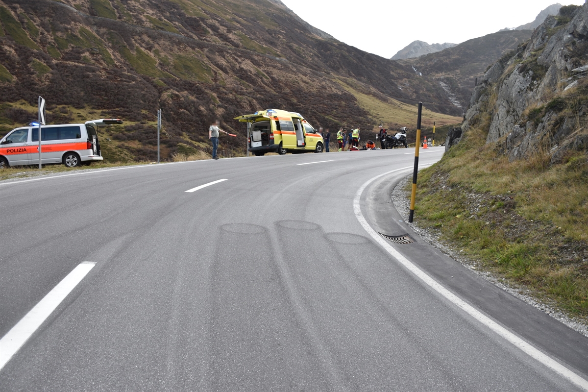 Scharfe, unübersichtliche Rechtskurve auf der Oberalpstrasse Richtung Oberalppass. Am linken Strassenrand im Hintergrund wird neben dem Sanitätsfahrzeug der verletzte Motorradlenker notfallmedizinisch versorgt.