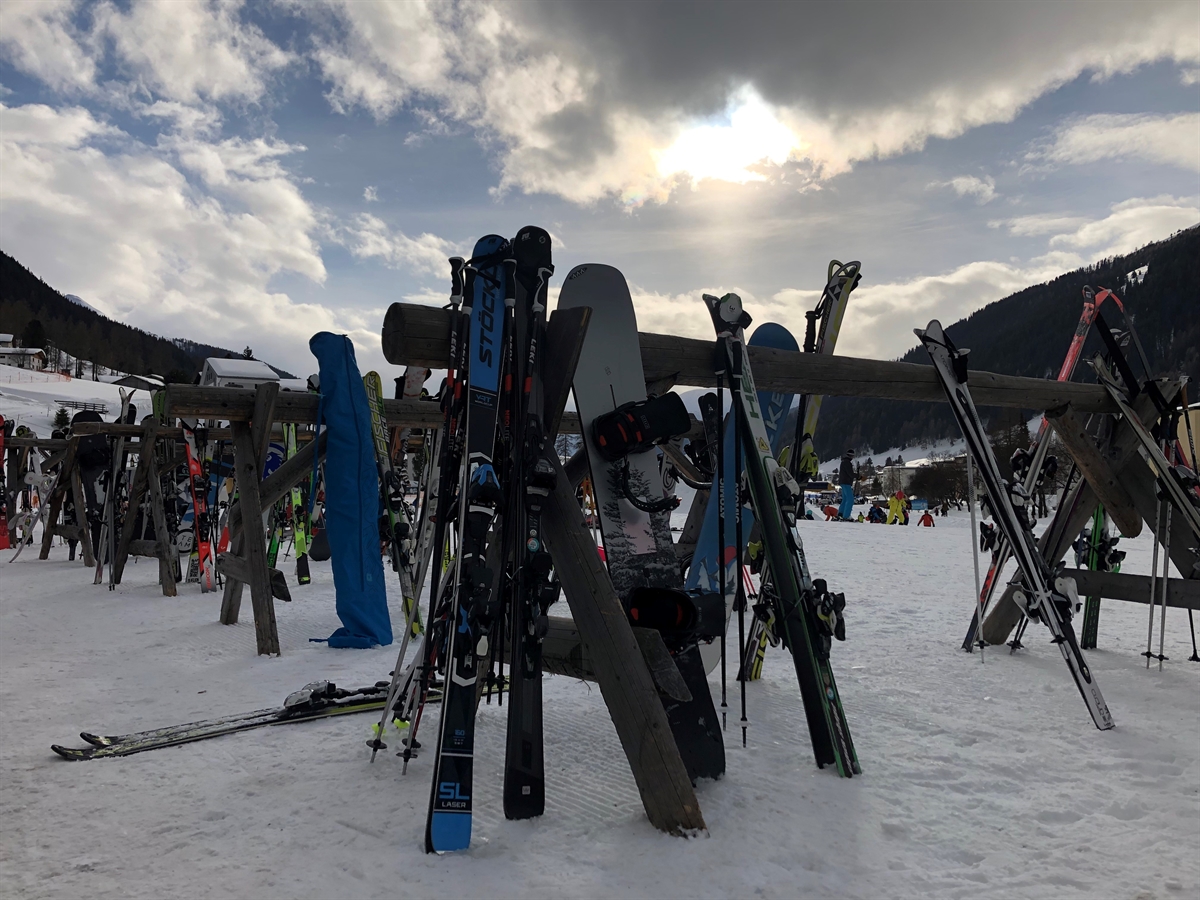 Mehrere Skiständer mit Snowboard und Skier in einer Winterlandschaft einer Tourismusdestination in Graubünden.