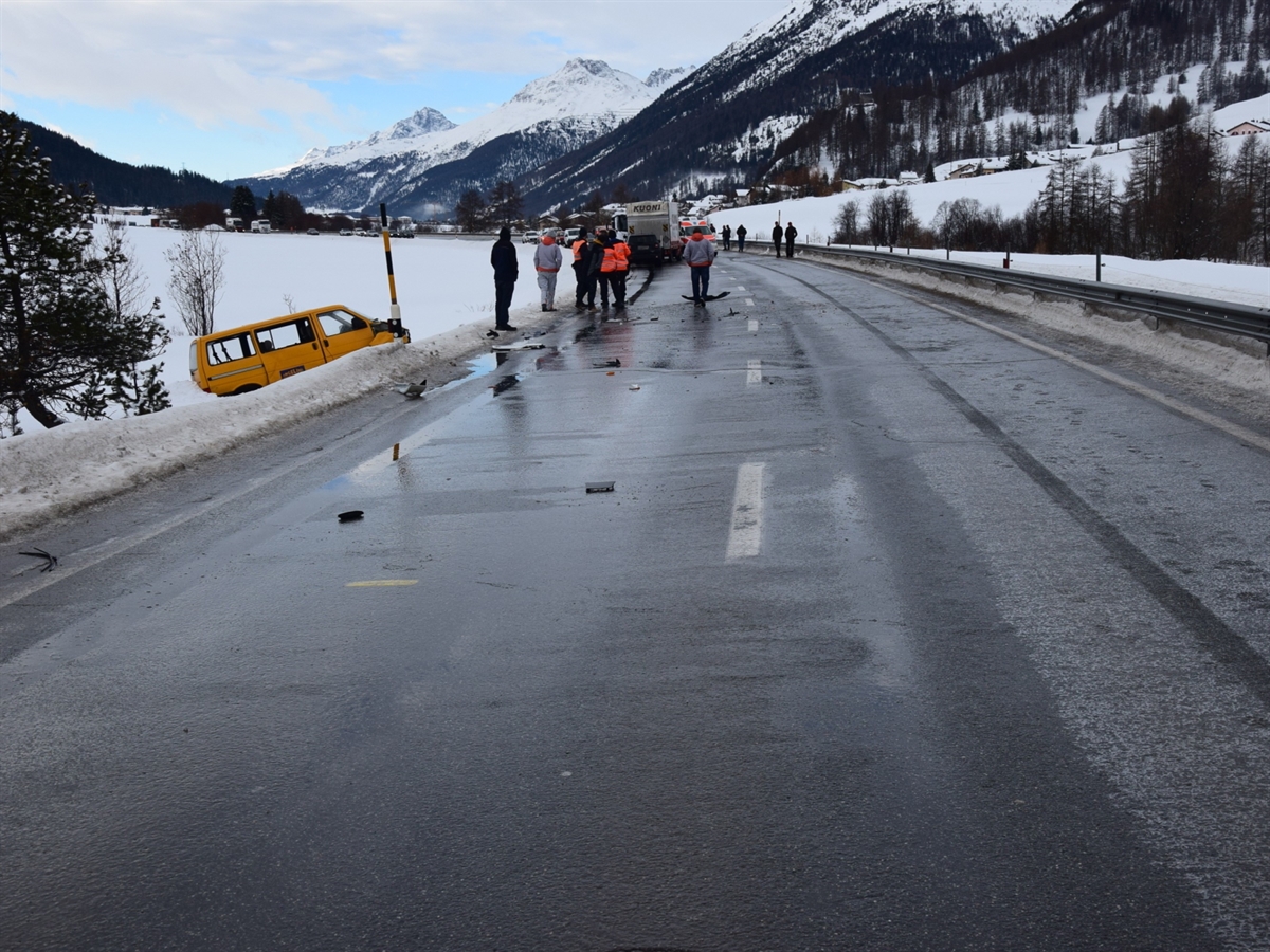 Vereiste Fahrbahn der Engadinerstrasse. Neben der Strasse liegt ein VW-Bus. Auf der Strasse befinden sich mehrere Personen. Im Hintergrund ein Lastwagen sowie ein Ambulanzfahrzeug