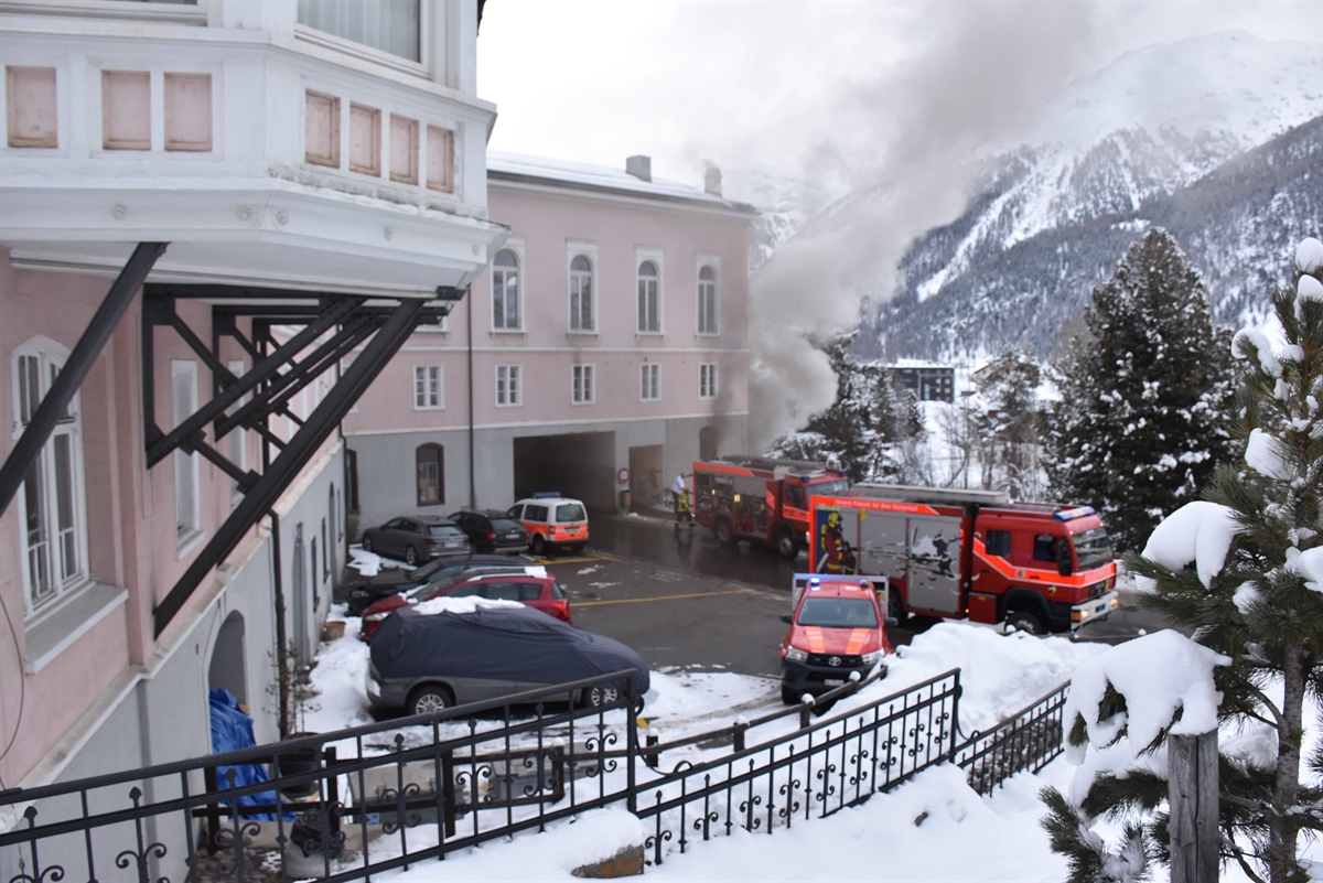 Übersichtsaufnahme vom Hotel mit Rauchentwicklung aus Fenstern und mehrere Feuerwehrfahrzeuge vor dem Hotel auf der Strasse.