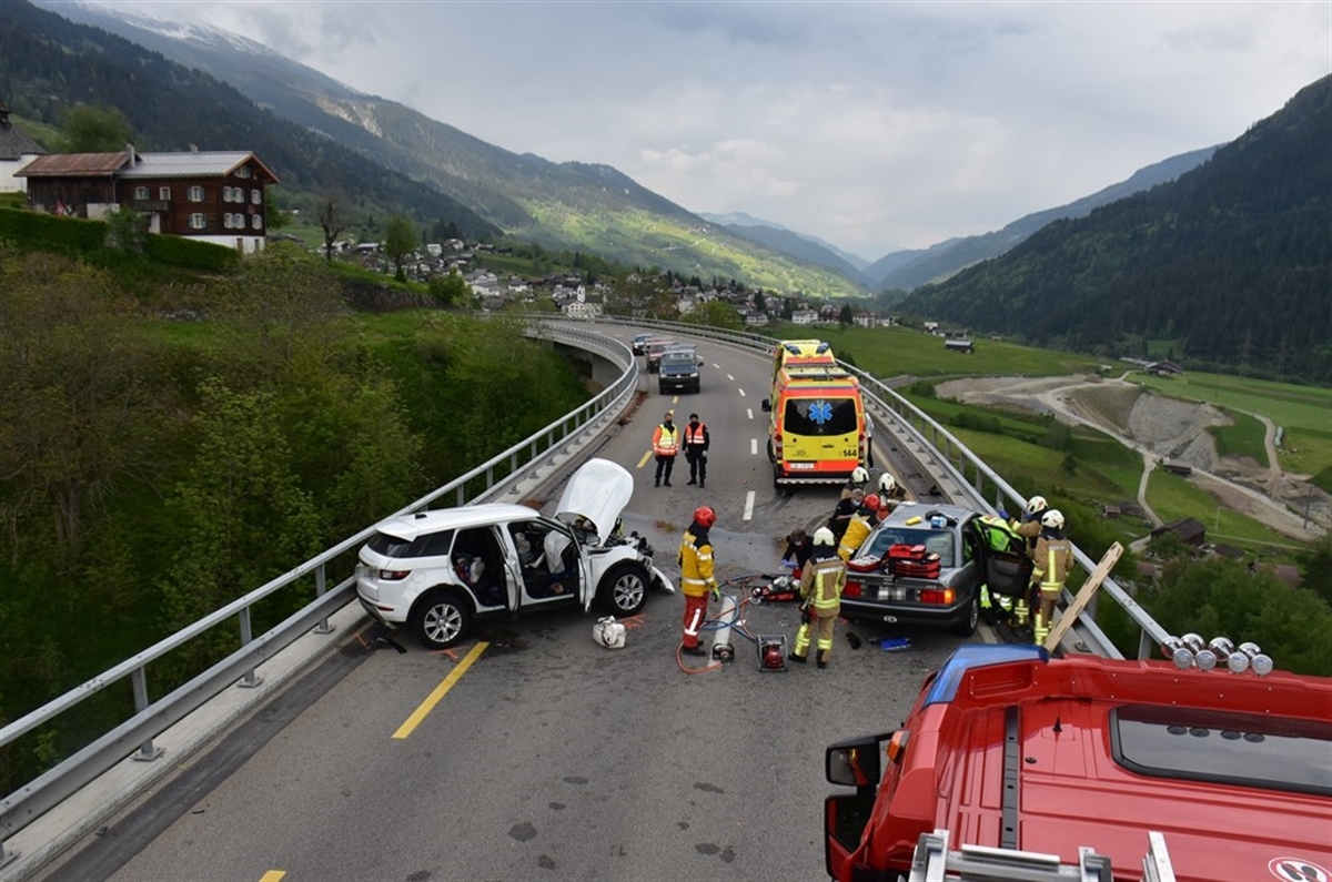 Verkehrsunfall auf einer Brücke mit zwei beteiligten Fahrzeugen (total beschädigt), einem Feuerwehrauto, einer Ambulanz sowie verschiedene Einsatzkräfte auf der Unfallstelle