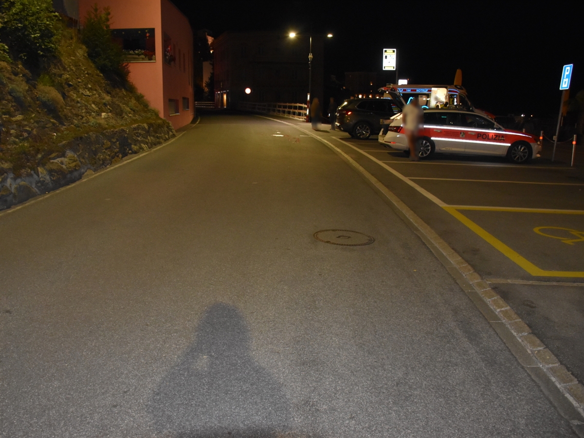 Nachtaufnahme der Via Stradun in Scuol mit den rechtsseitig eingezeichneten Parkfeldern. Auf einem Feld steht ein Patrouillenfahrzeug der Kapo GR und auf einem anderen ein Ambulanzfahrzeug.