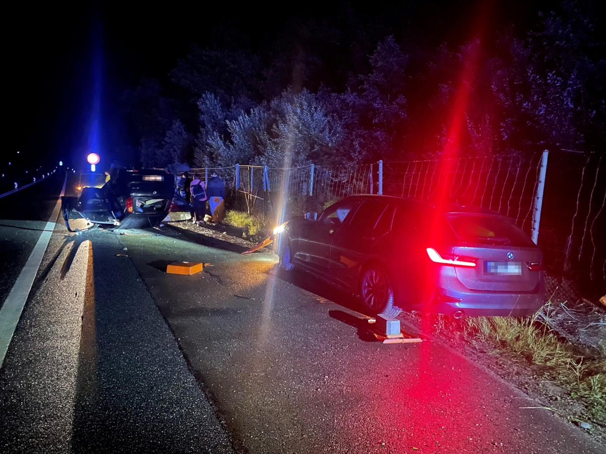 Nachtaufnahme mit dem einen am Unfall beteiligten Personenwagen im Vordergrund sowie dem anderen auf dem Dach liegenden Auto im Hintergrund.