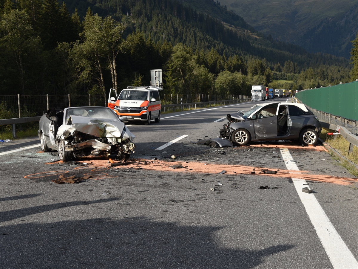 Zwei total beschädigte Fahrzeuge auf der Autostrasse A13. Im Hintergrund ein Patrouillenfahrzeug der Kantonspolizei Graubünden sowie der aufkolonierte Schwerverkehr.