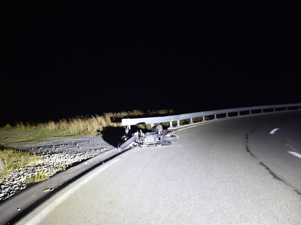 Nachtaufnahme mit beleuchtetem auf der Strasse liegendem Motorrad.