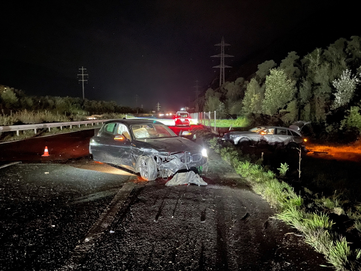 Nachtaufnahme, im Vordergrund ein schwarzes Auto auf dem Pannenstreifen. Rechts davon ein wenig weiter entfernt in der angrenzenden Wiese ein graues Auto. Beide Fahrzeuge sind total beschädigt.