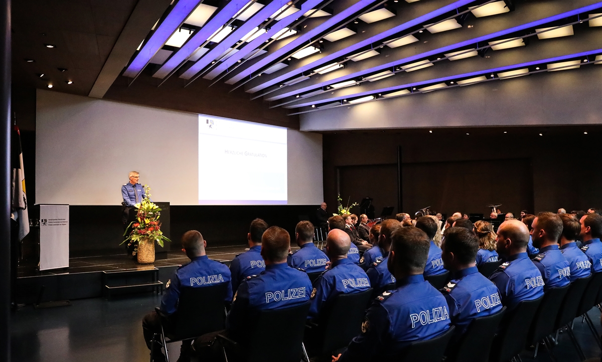 Kommandant auf der Bühne spricht zu Uniformierten, im Hintergrund die Polizeimusik