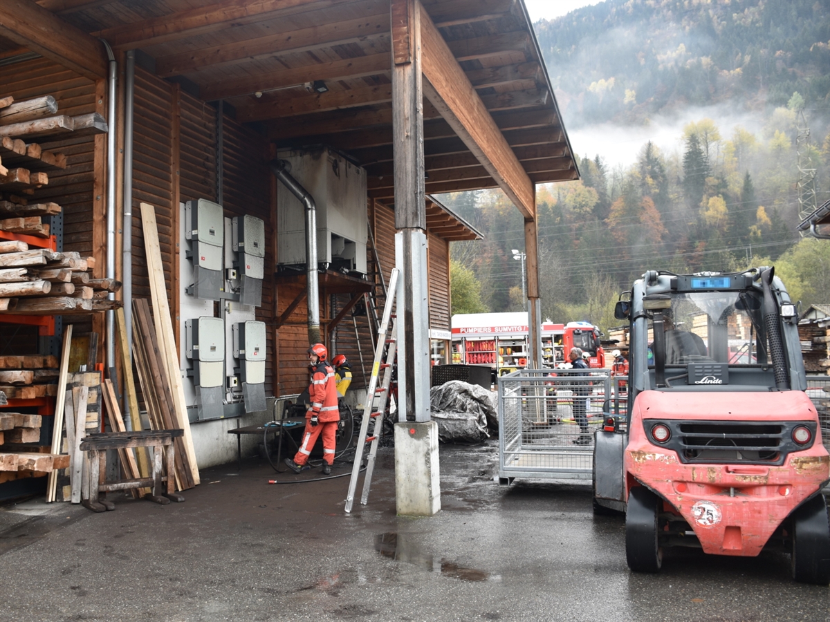 Gewerbegebäude mit der Absauganlage. Im Hintergrund ein Feuerwehrauto mit Einsatzkräften. Rechts im Bild ein Stapler, der zur Unterstützung der Löscharbeiten eingesetzt wurde.