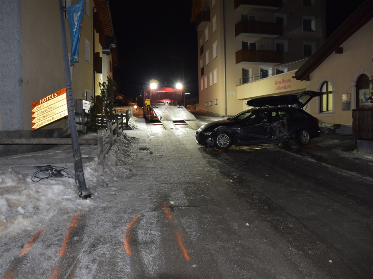 Die schneebedeckte Via Staziun in Zuoz. Quer zur Fahrbahn steht das total beschädigte Unfallfahrzeug. Am linken Bildrand ist das Kandelaber sowie der Zaunpfosten zu sehen. Im Hintergrund das Fahrzeug des Abschleppdienstes.