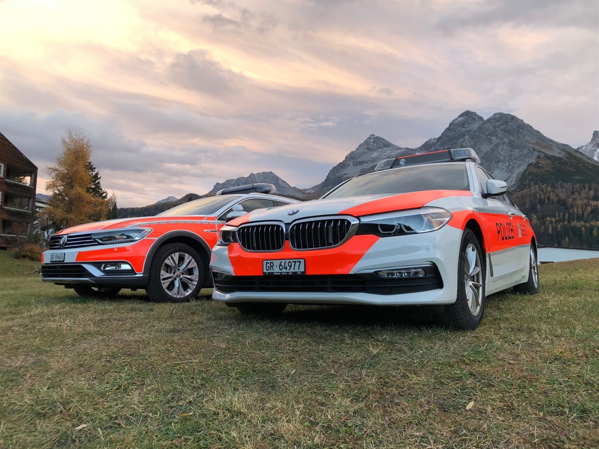 Zwei Patrouillenfahrzeuge der Kantonspolizei Graubünden vor traumhafter Bergkulisse.