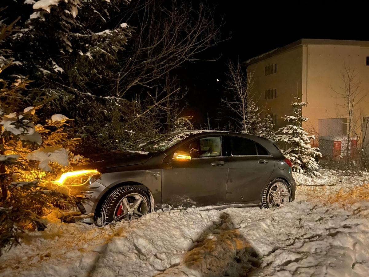 Nachtbild der Winterlandschaft. Das Auto steht im Schnee. Die Motorhaube steckt im Gebüsch. Im Hintergrund ein Haus.