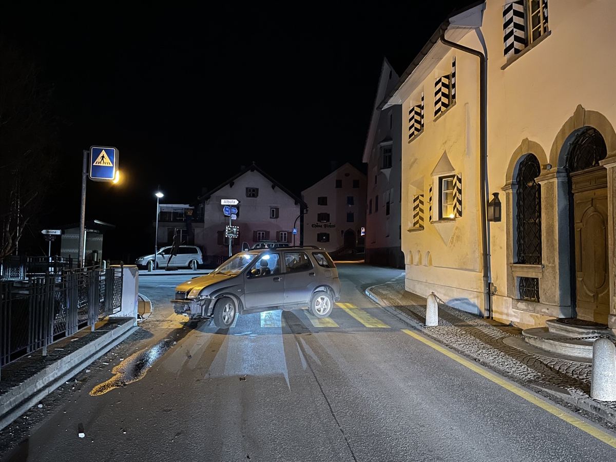 Nachtaufnahme – Rechts ein Haus, links davon das vorne rechts stark beschädigte und abgedrehte Auto. Es steht auf einem Fussgängerstreifen.