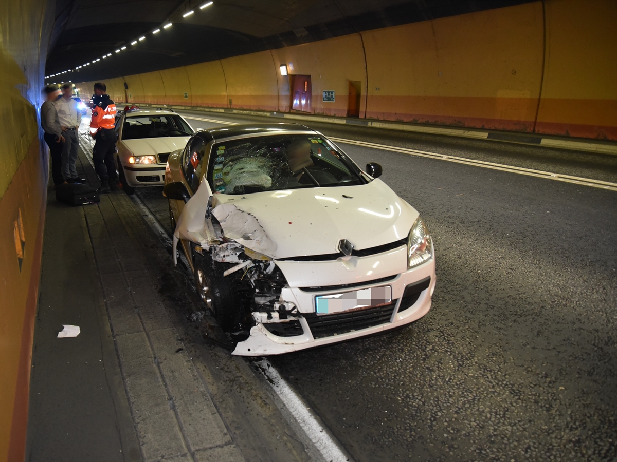 Aufnahme im Tunnel: Frontaufnahme des aufgefahrenen Autos, die Front stark beschädigt. Dahinter das vorausgefahrene Auto, ein Polizist und ein Polizeiauto.