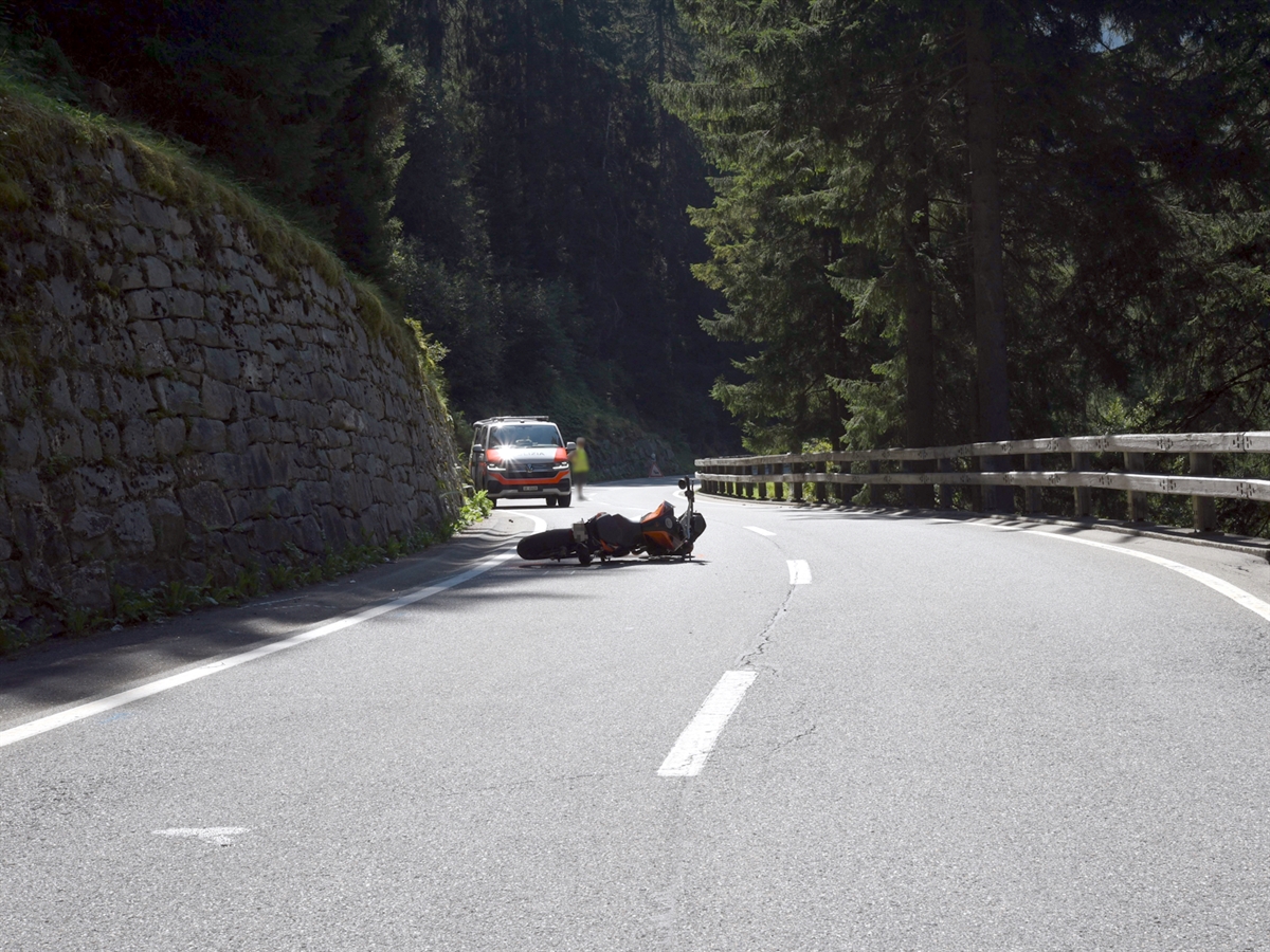 Auf der Talspur liegt das Motorrad auf der rechten Fahrzeugseite. Hinter diesem steht ein Patrouillenfahrzeug der Polizei. Daneben steht eine Privatperson, die den Verkehr regelt.