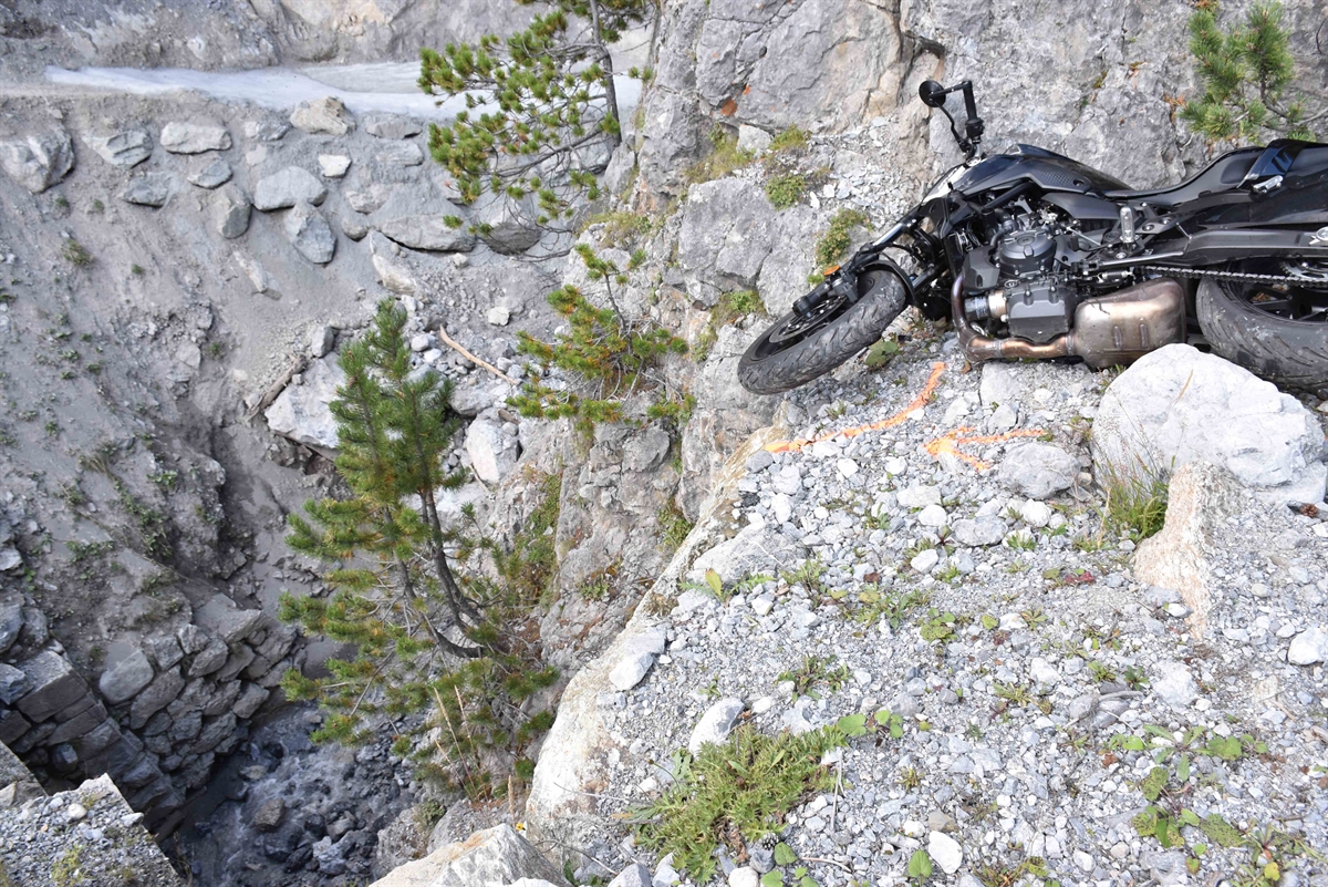 Das Motorrad liegt rechtsseitig am Boden im Geröll unmittelbar vor dem Abgrund/Felswand zu dem zirka 10 Meter tieferen Bachbett.