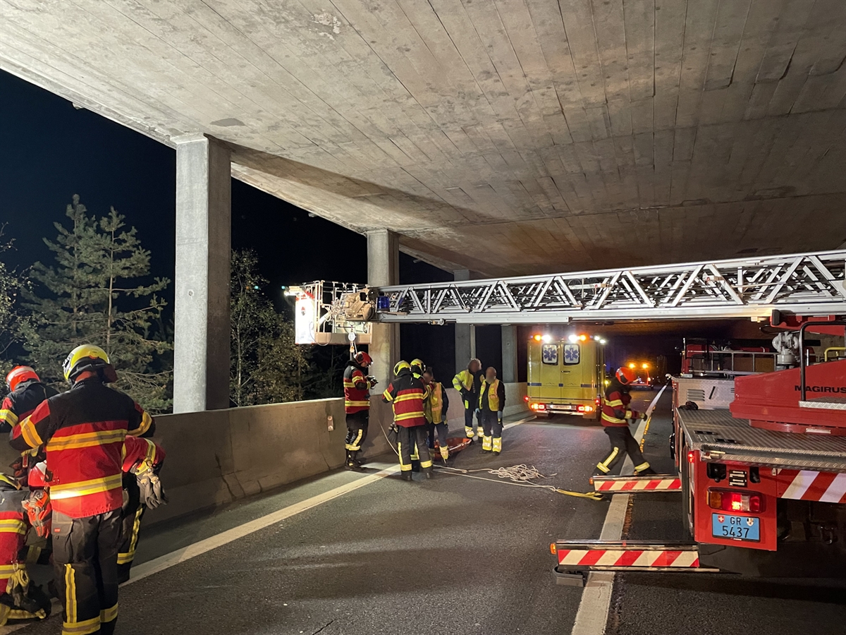 Feuerwehrleute der Strassenrettung Thusis bedienen den Hubretter in der Trögli-Galerie. Ein Team der Rettung Mittelbünden bereitet sich für die Betreuung des Verletzten vor.