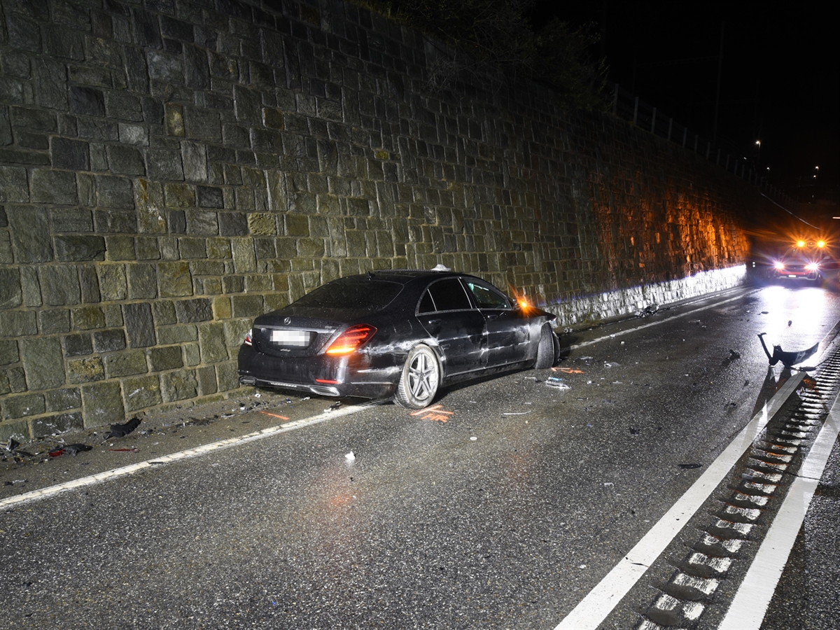 Die Limousine steht linksseitig bei der Stützmauer. Im Hintergrund ein Patrouillenfahrzeug der Kantonspolizei Graubünden.