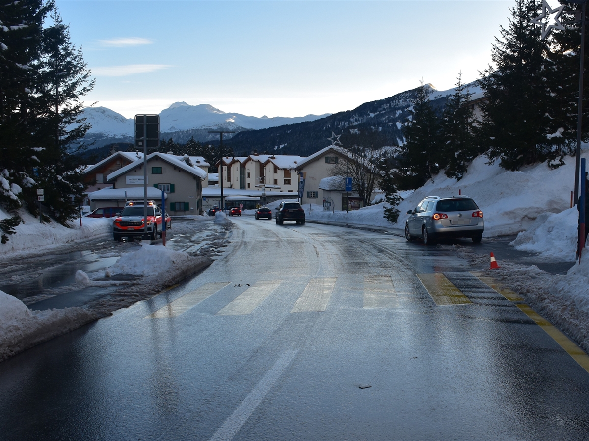 Der Fussgängerstreifen eingangs Valbella mit dem Beteiligten Auto am rechten Bildrand. Links zwei Patrouillenfahrzeuge der Kantonspolizei Graubünden. Das Bild wird in ein abenddämmerndes Licht eingehüllt.